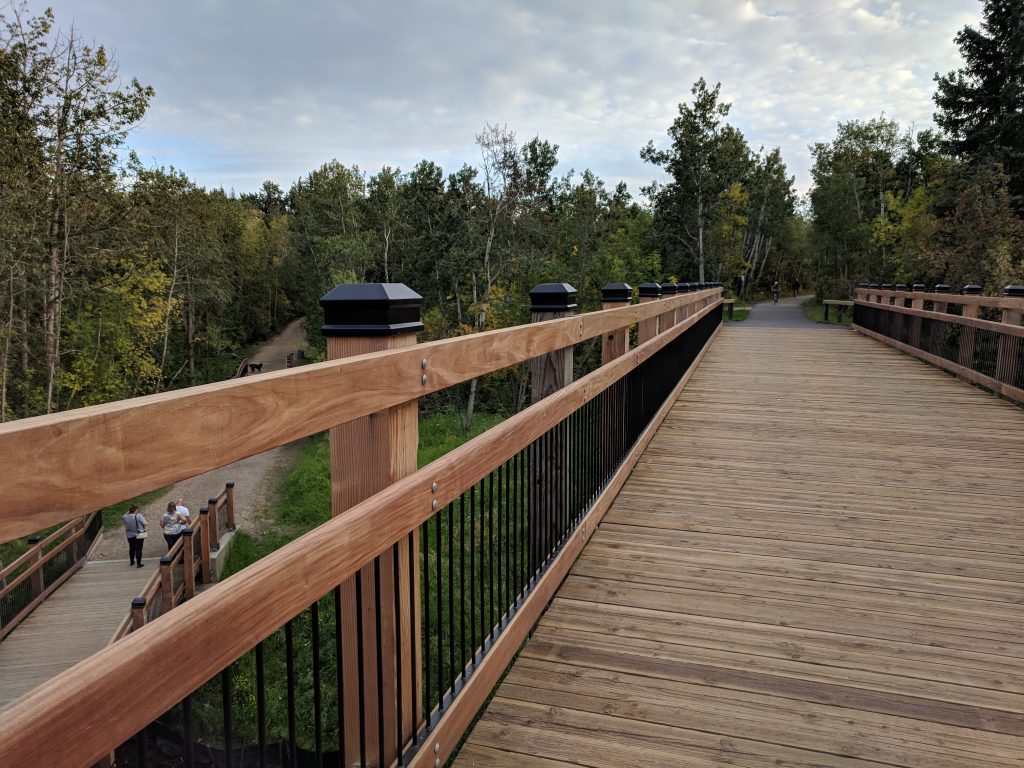 A wooden boardwalk bridge on a wooded trail