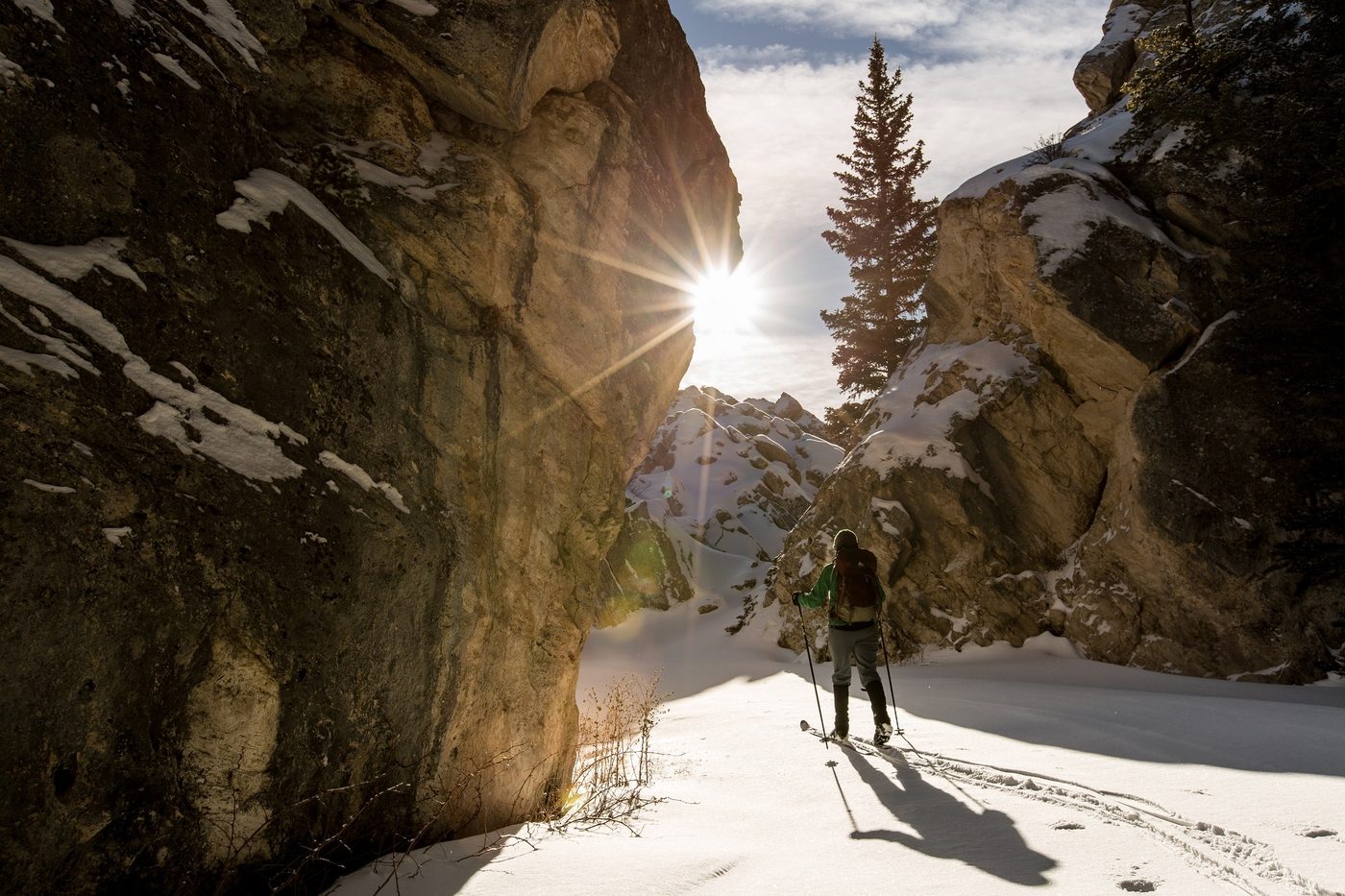 A cross-country skier in a sunlit snowy canyon